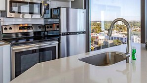 A modern kitchen with stainless steel appliances, a large window, and a city view. - SEAGLASS TOWER MYRTLE BEACH 6 NIGHTS Sept 28-Oct 4,2026 DELUXE OCEANFRONT 1 BDRM (Myrtle Beach)