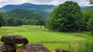 A grassy landscape with large rocks, trees, and a hilly background. - ML 270: Dazzling 3BR with unbeatable mountain views! Bike-in/out! (Snowshoe)