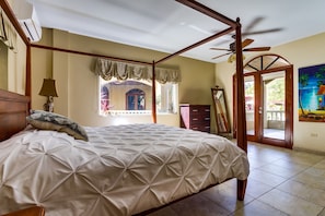 A four-poster bed with a canopy, a ceiling fan, and a view of the outside.