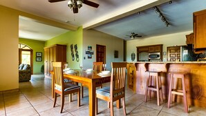 Una cocina amplia con armarios de madera, un comedor con mesa y sillas, y un ventilador de techo.