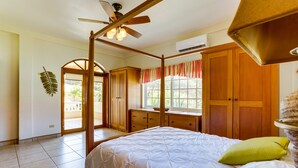 Un dormitorio con cama con dosel, armario de madera y ventana con cortinas.