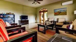Una sala de estar con televisión, sofás, una mesa de centro y una estantería.