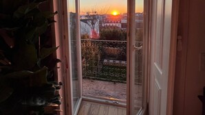 Ein Balkon mit Blick auf den Sonnenuntergang über einer Stadtlandschaft.