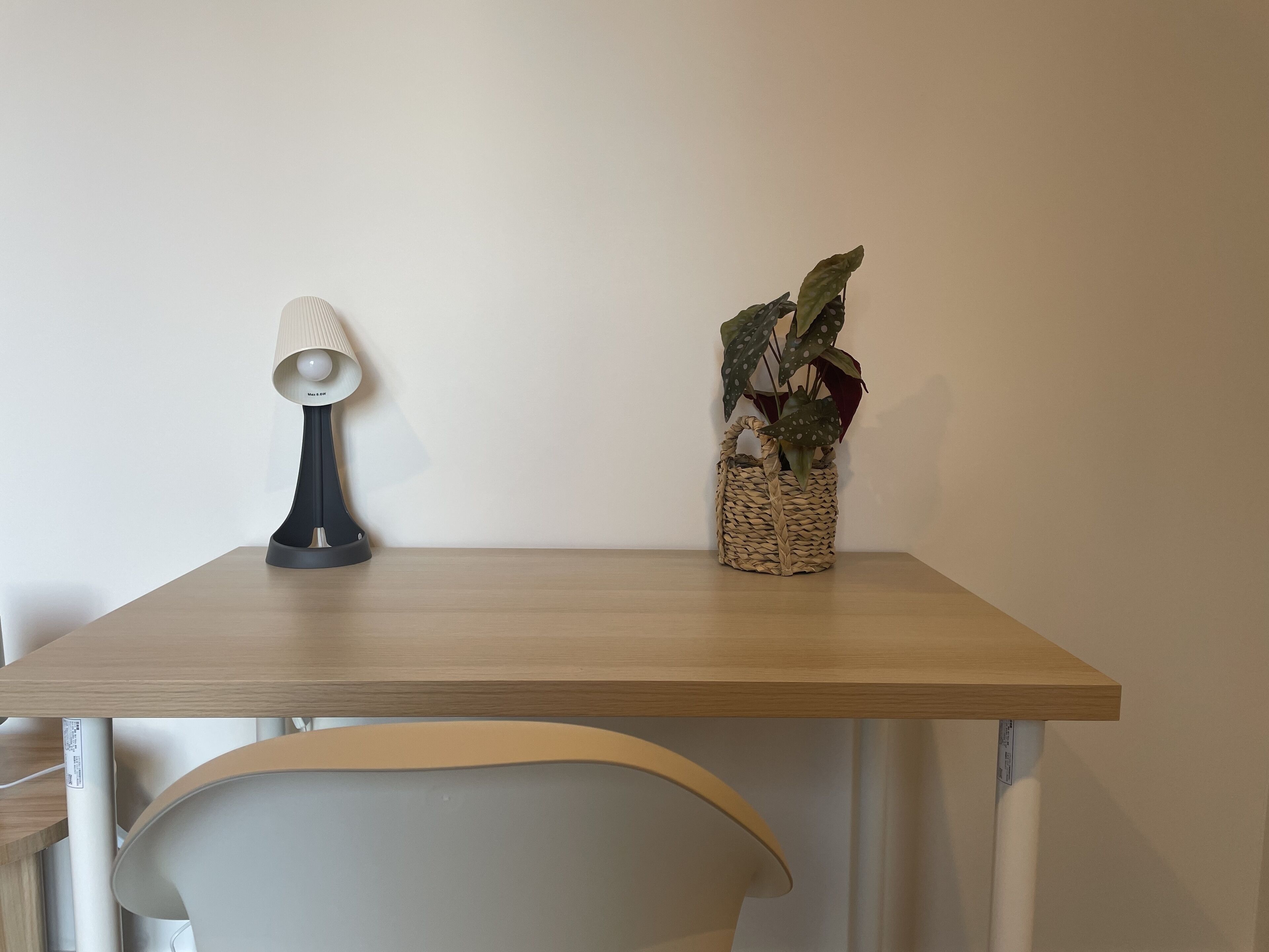 A wooden table with a lamp and a woven basket containing a plant.