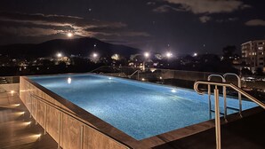 A nighttime view of a swimming pool with a clear sky and distant mountains.