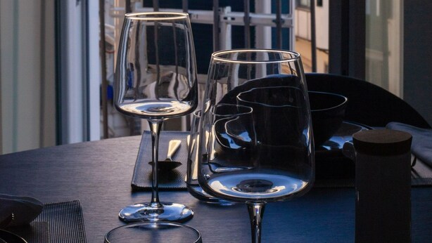 A table with two wine glasses and a coffee cup, overlooking a building with a dome and a red-roofed structure.