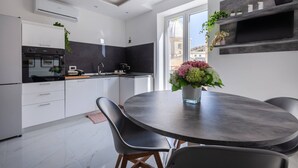 A modern kitchen with white cabinets, a black countertop, and a dining area with a round table and chairs.