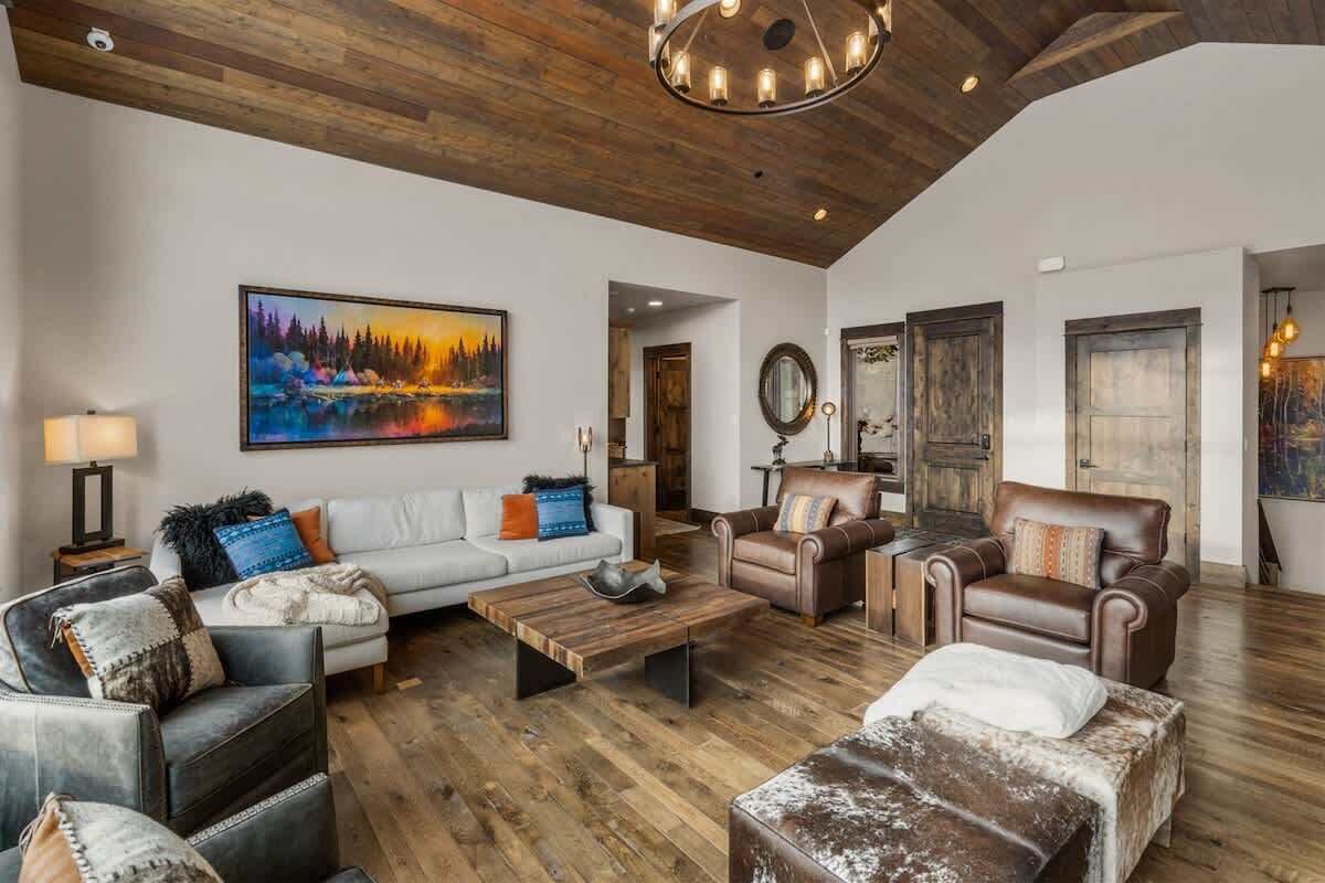 A spacious living room with a wooden ceiling, a large painting, and leather furniture.