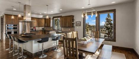 A modern kitchen with a central island, bar stools, and a dining table with benches.