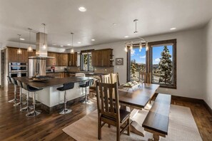 A modern kitchen with a central island, bar stools, and a dining table with benches.