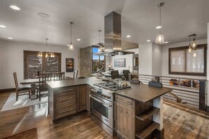 A modern kitchen with a central island, stainless steel appliances, and pendant lighting. - Ski-In/Ski-Out Updated Big Sky Retreat (Big Sky)