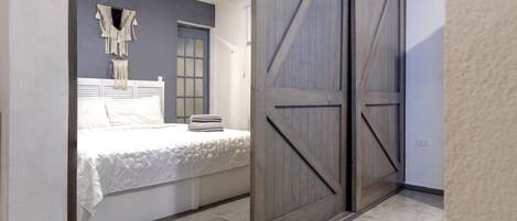 A bedroom with a bed, a wall-mounted macrame decoration, and a wooden door.