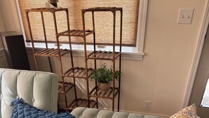 Ein hellgrünes Sofa mit blauer Decke und einem gemusterten Kissen, ein Holzpflanzentisch mit Blumentopf und ein gemusterter Teppich auf Holzboden.