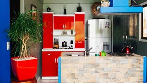 Una cocina moderna con gabinetes rojos, una isla central y diversos electrodomésticos.