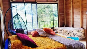 Una habitación acogedora con una cama, una silla colgante y un banco de piedra.