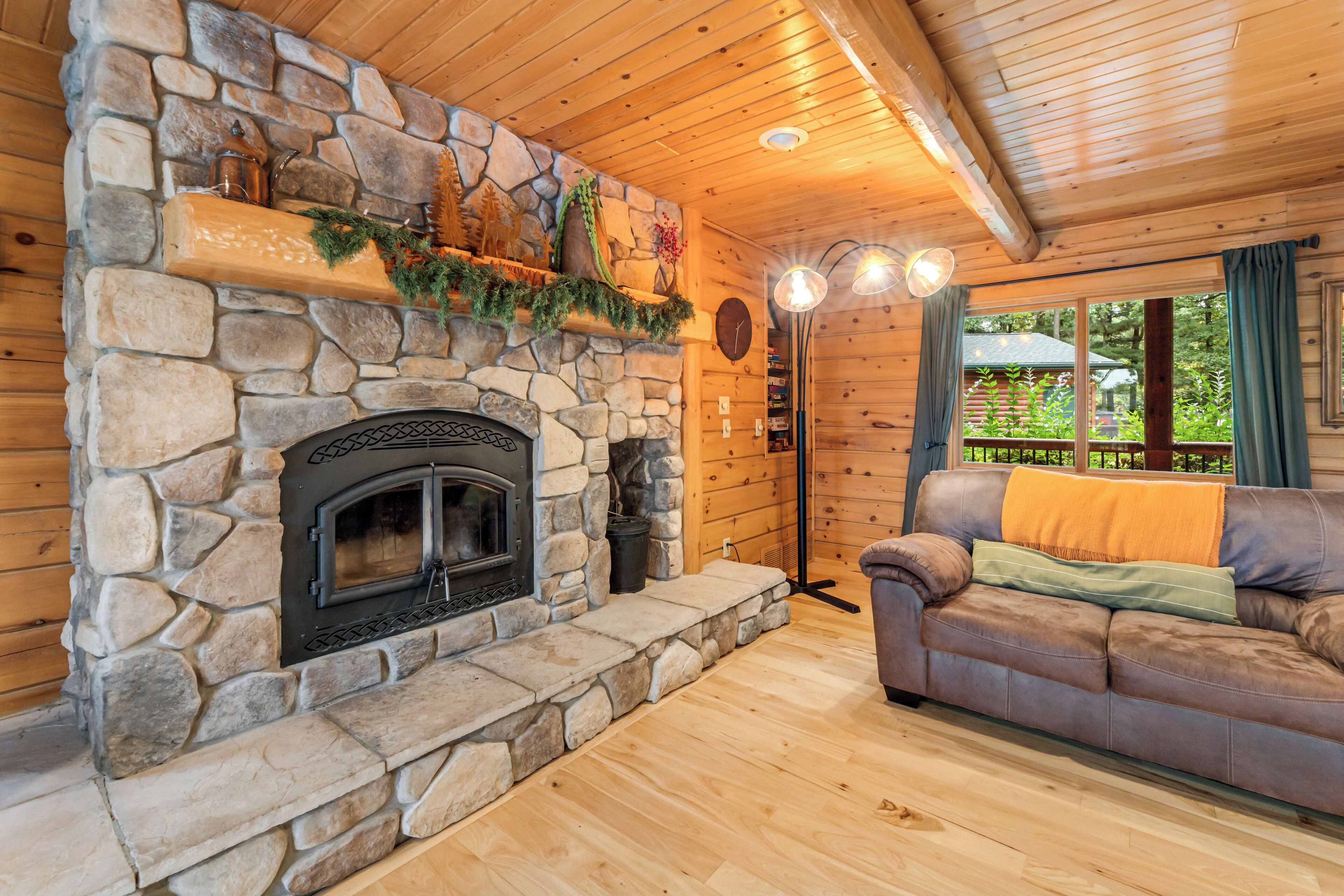A stone fireplace with a mantel, a leather sofa, and a wooden floor.