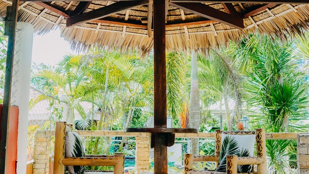 A thatched-roof structure with two wooden chairs and a small table, surrounded by lush greenery. - Private quite bungalow-5 min walk to ocean & restaurants (Moalboal)