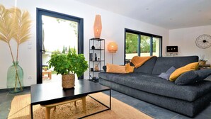 A modern living room with a grey sofa, a black coffee table, and a large potted plant. - Stunning home in Montfavet (Montfavet)