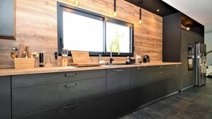 A modern kitchen with a large window, dark cabinetry, and a built-in refrigerator. - Stunning home in Montfavet (Montfavet)