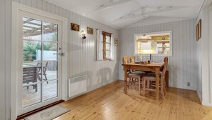 A dining area with a wooden table and chairs, a window with curtains, and a view of the outdoors. - Awesome home in Stege with WiFi (Stege)