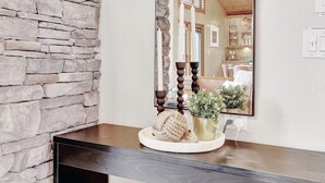 Un miroir reflétant une pièce avec un mur en pierre, un plafond en bois et un lustre.