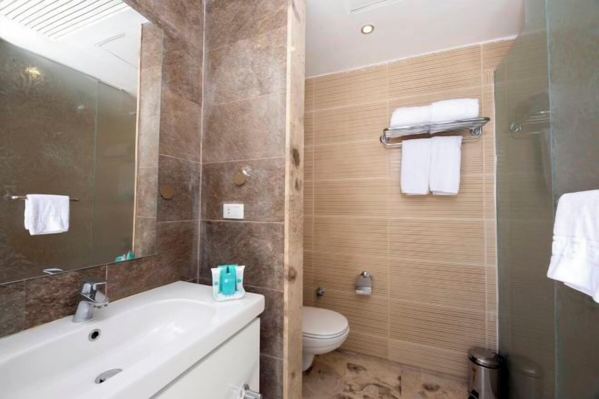 Een moderne badkamer met een ruime badkuip, toilet en een douchecel met glazen wanden.
