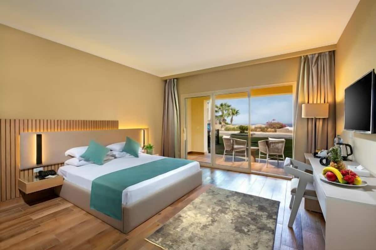 Une chambre d’hôtel équipée d’un lit, d’un bureau, d’une chaise, d’une télévision et d’un balcon avec vue.