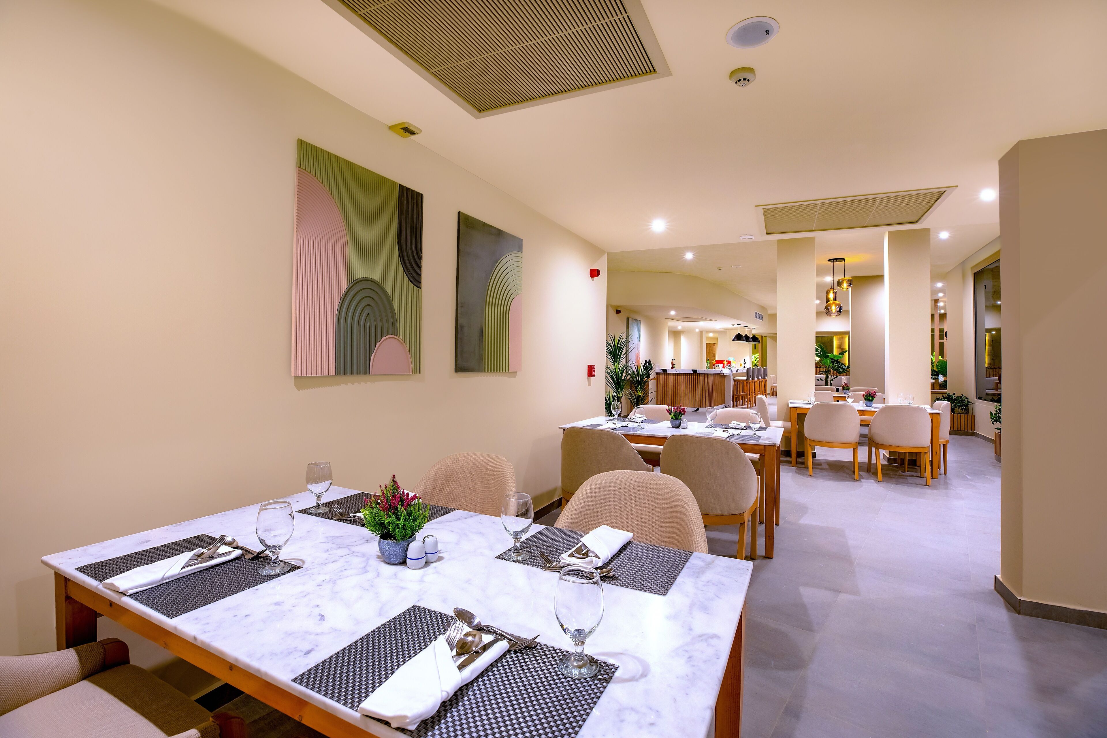 A dining area with marble tables, chairs, and artwork on the walls.