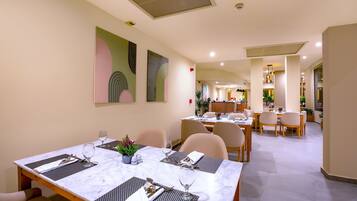 A dining area with marble tables, chairs, and artwork on the walls.