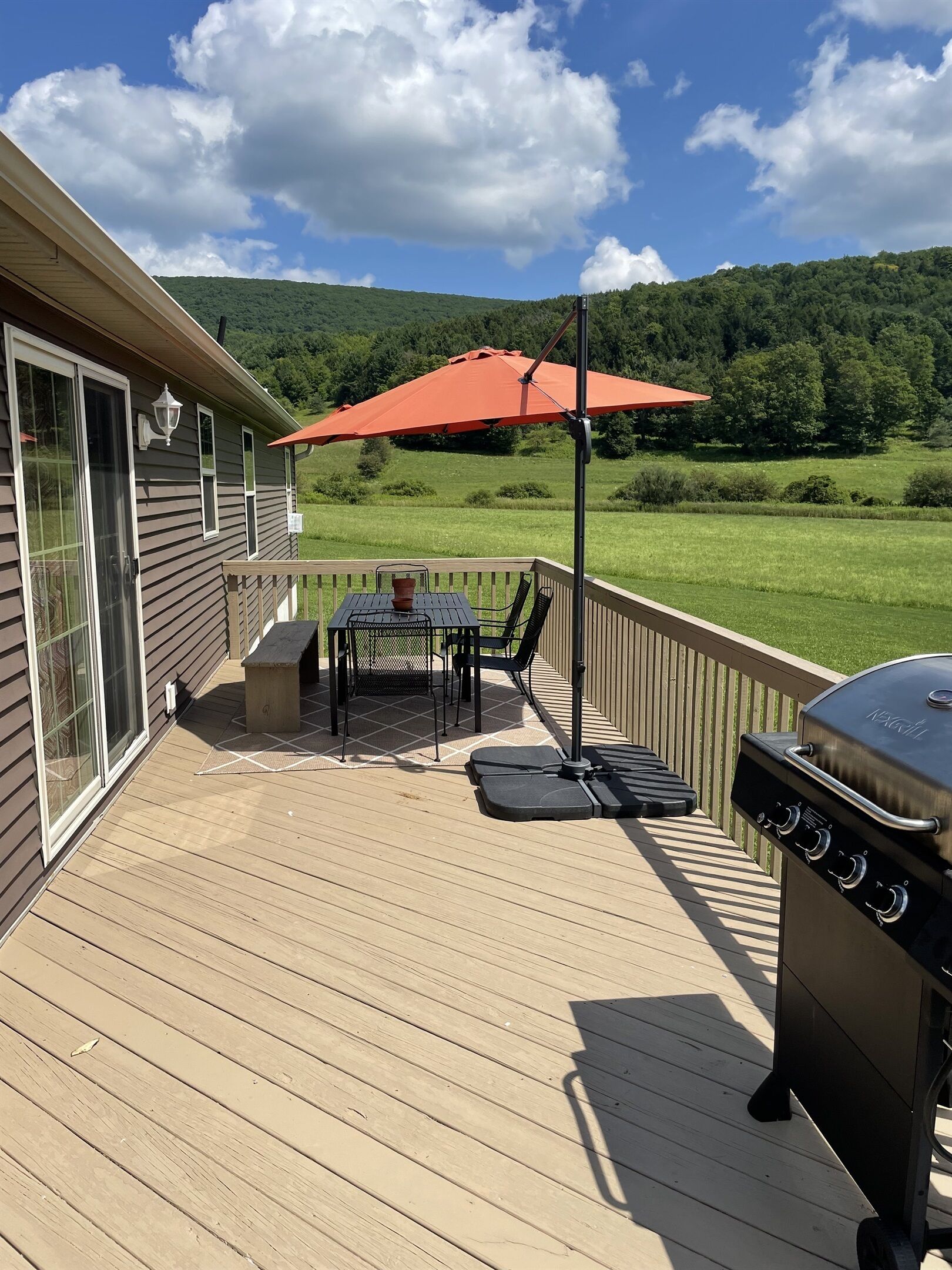 A deck with a table, chairs, and a grill.