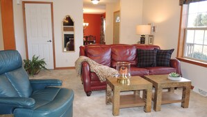 A living room with a blue leather sofa, a red leather couch, and a wooden coffee table. - Drive It Home Recent New Construction, 5 minutes to Dreams Park or Cooperstown (Cooperstown)