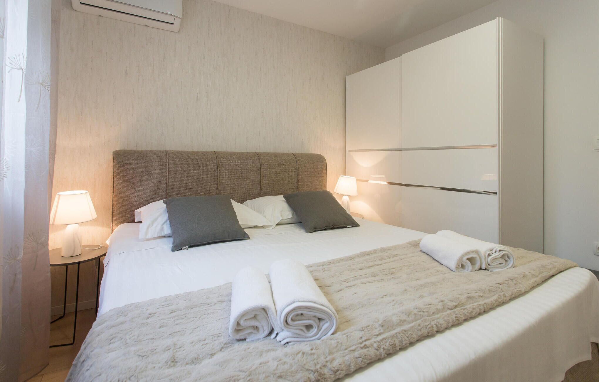 Ein Hotelzimmer mit einem Bett, zwei Nachttischlampen, einem Kleiderschrank und einem Fenster mit Vorhängen.
