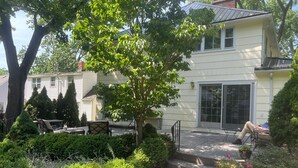 Een woonwijk met een huis, voorzien van een groot raam en een overdekt terras.
