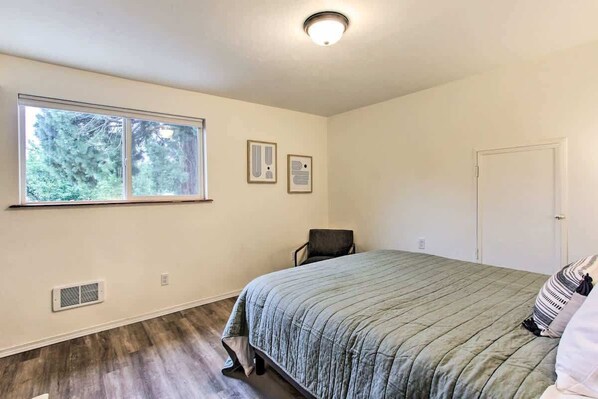 A bedroom with a bed, a chair, a window, and a door.
