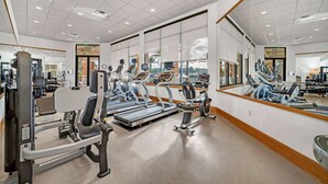 A gym with cardio machines, weight training equipment, and large mirrors.