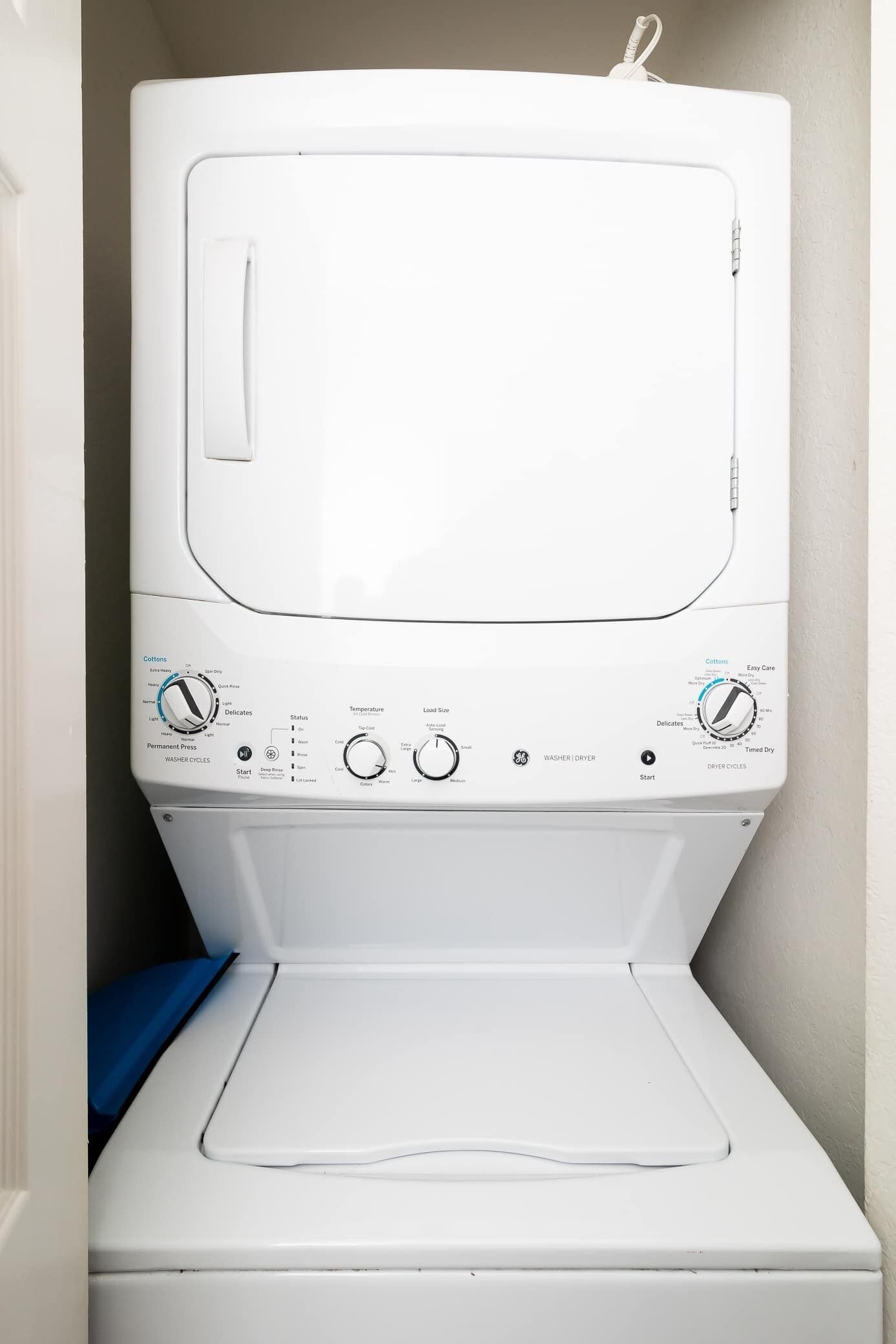 A front view of a white washing machine with control knobs and a front-loading door.