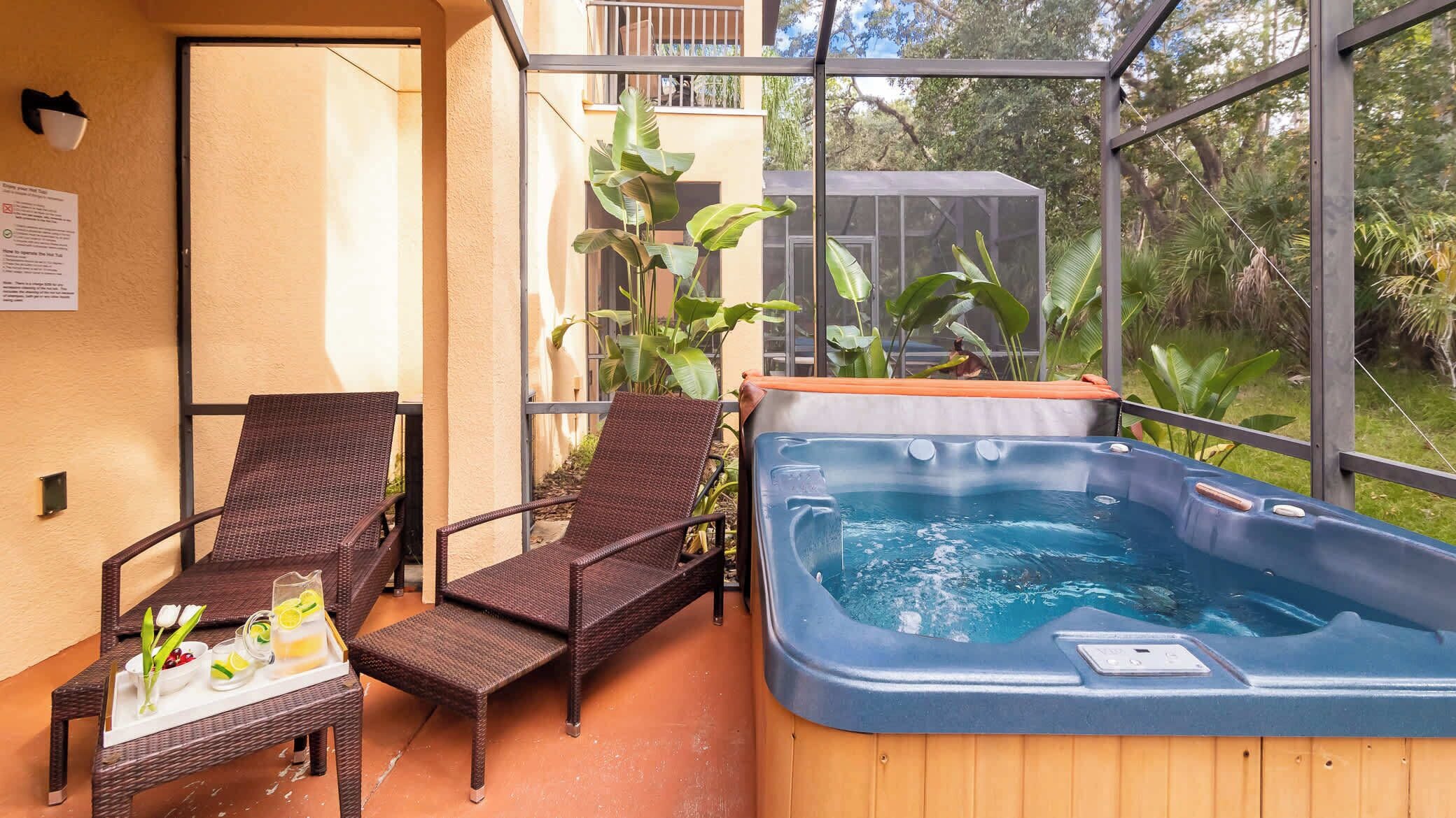 En balkon med fletstole, jacuzzi og en bakke med drikkevarer.