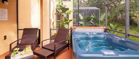 En balkon med fletstole, jacuzzi og en bakke med drikkevarer.