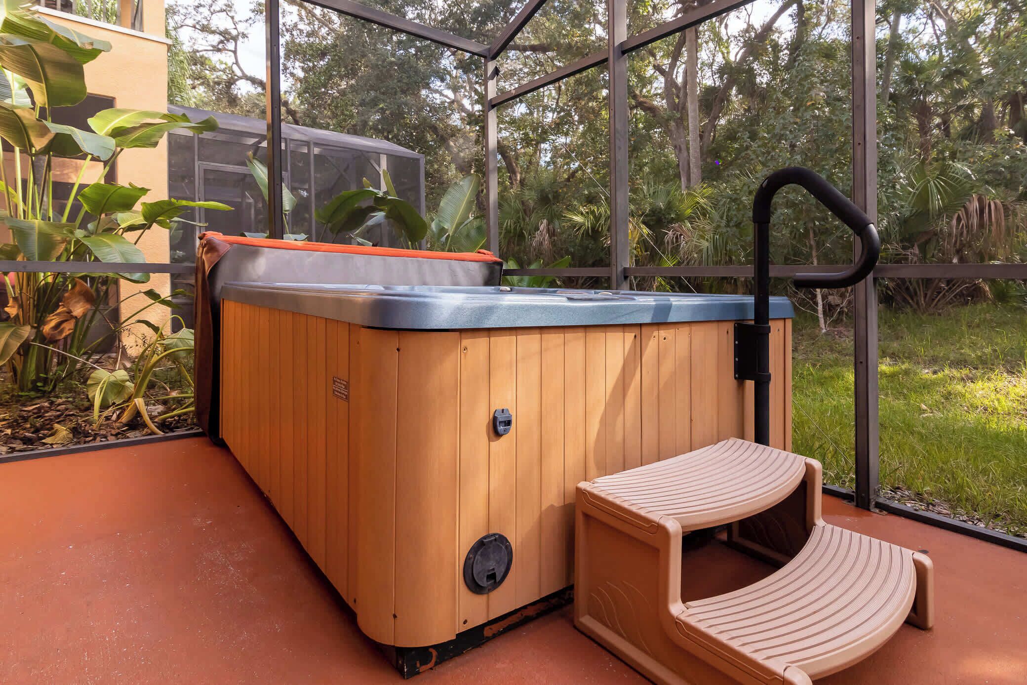 Un bain à remous en bois, doté d’un siège intégré et d’un panneau de commande, installé sur une terrasse avec une paroi vitrée donnant sur un jardin.