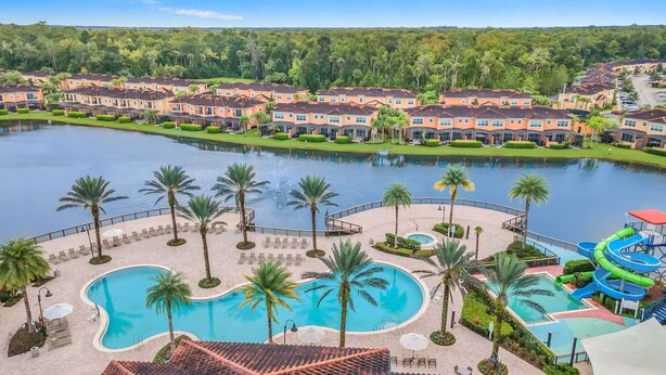 A resort with multiple swimming pools, a water slide, and a lake.