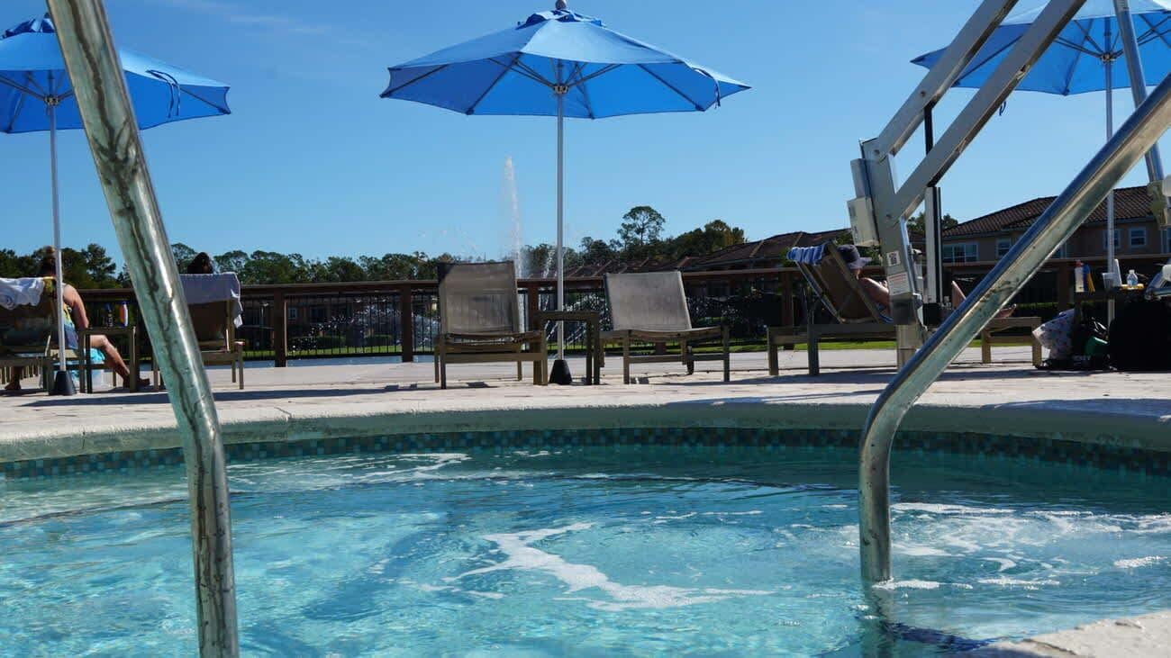 A swimming pool with blue umbrellas and lounge chairs.