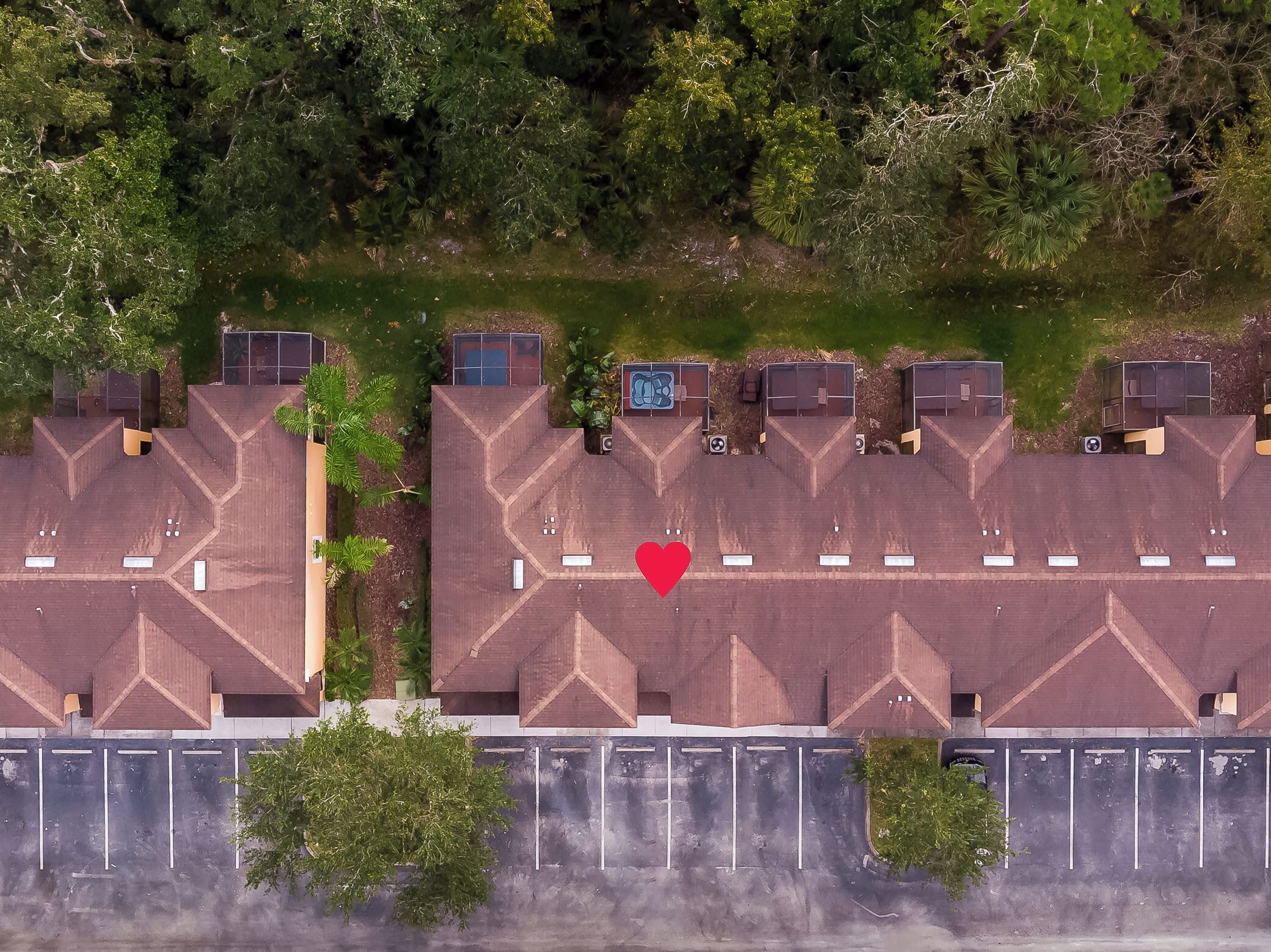 An aerial view of a parking lot with multiple buildings, surrounded by dense greenery.