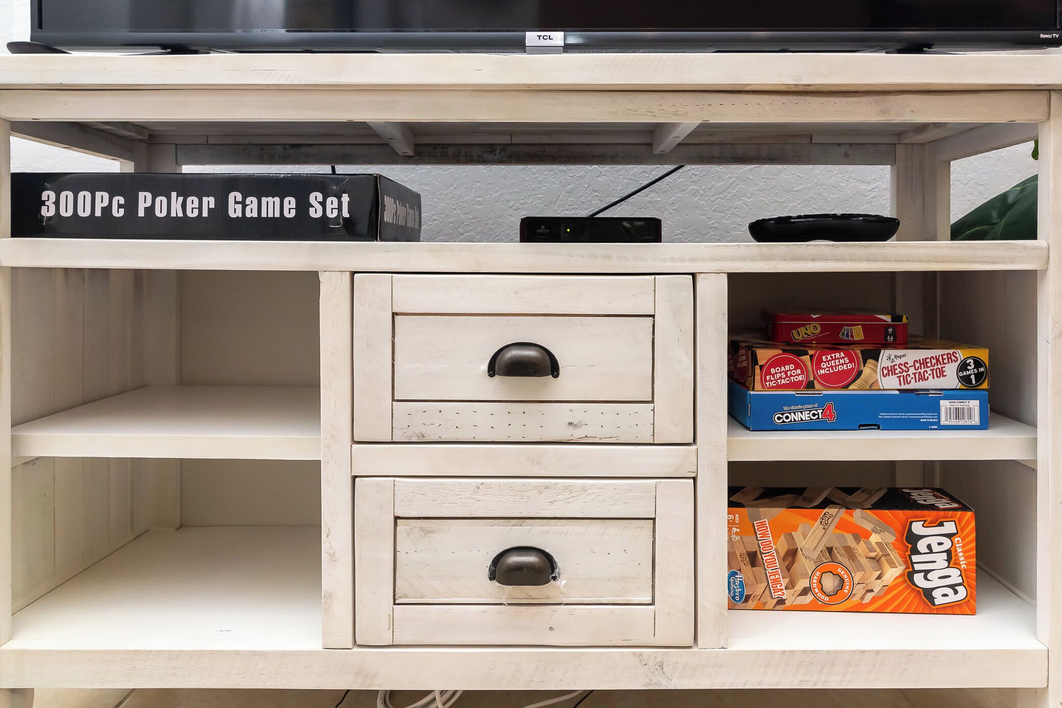 A shelf with a 300Pc Poker Game Set, a chess set, and a Jenga box.
