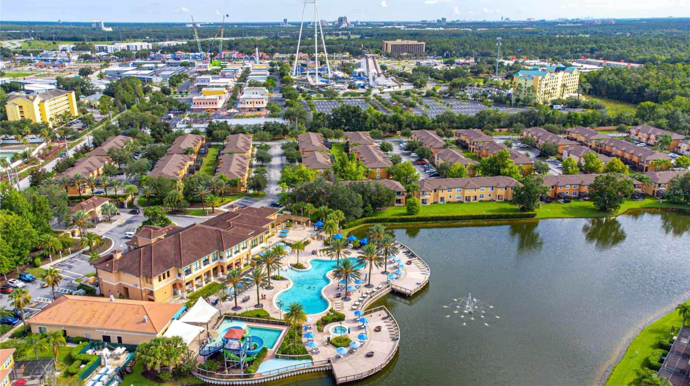 Un resort con varias construcciones, una piscina grande y un lago.