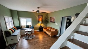 A living room with a sofa, a round coffee table, a lamp, and a ceiling fan.