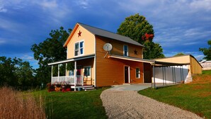 A two-story house with a porch, a garage, and a gravel driveway.