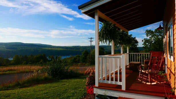 A wooden porch with a view of a lake and hills.