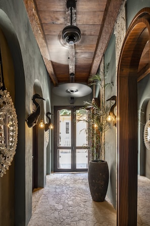 A hallway with a stone floor, wooden beams, and a large potted plant. - Privado Designer Boutique Hotel (Cartagena)
