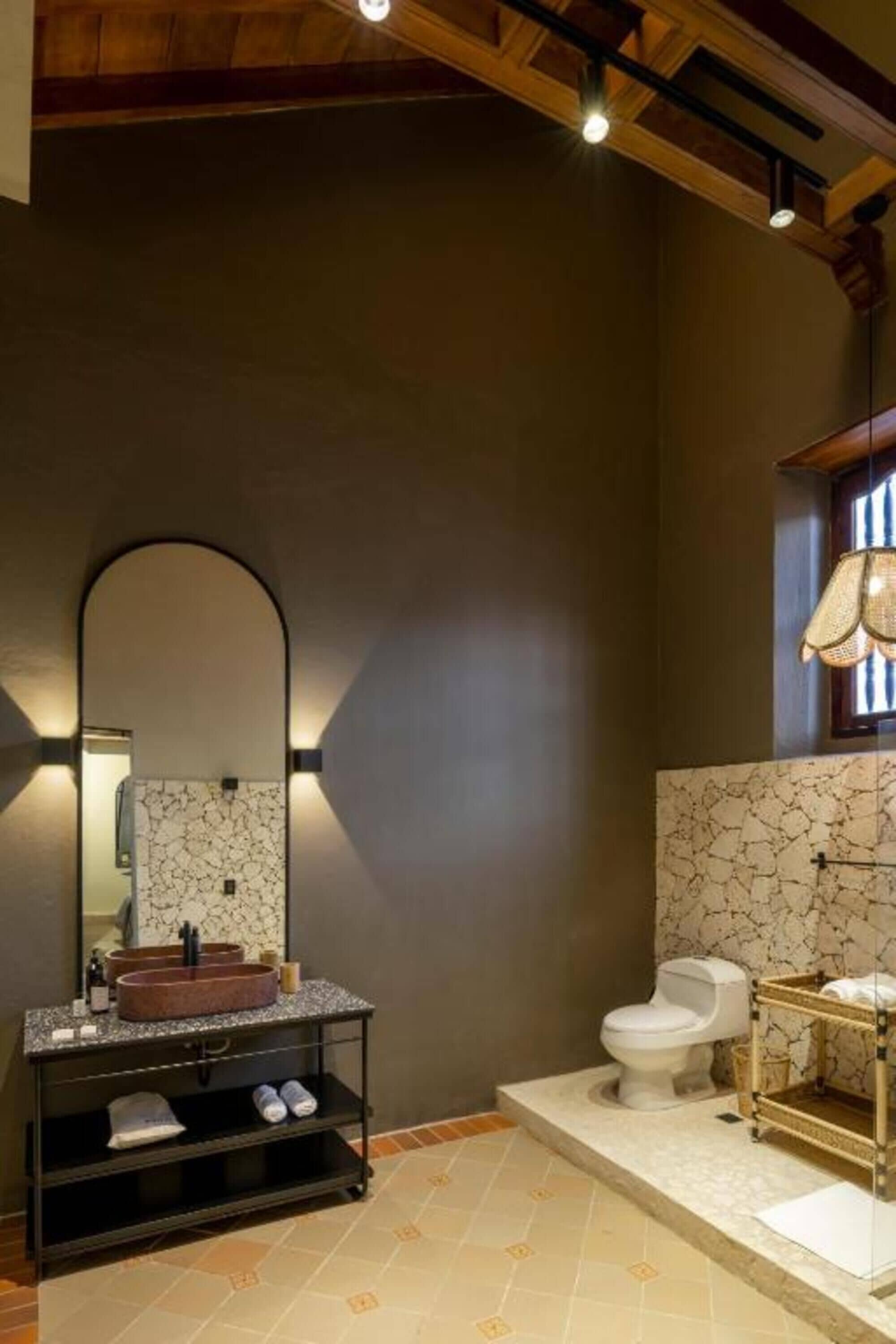 Een moderne badkamer met een vrijstaand wastafelmeubel, een grote spiegel en een toilet.