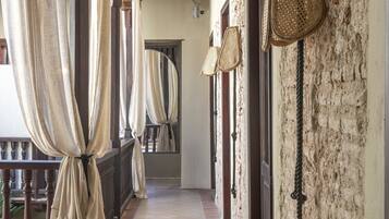 A corridor with wicker chairs, a wooden ceiling, and a stone wall.